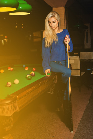 Glamour beauty woman plays billiard on pool table.の写真素材