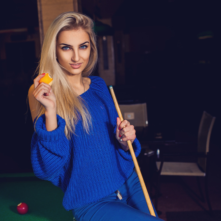 young blonde with blue eyes and cue ball in hands.の写真素材