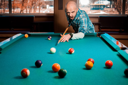 young guy plays pool billiard.
