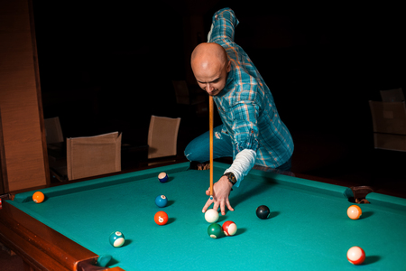 man chooses a difficult hit on pool billiards.の写真素材