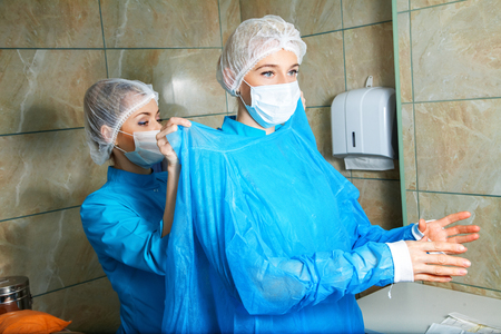 Young woman doctor preparing for the operation with an assistant.の写真素材