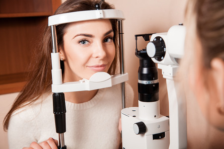 Lovely Young adult woman is having eye exam performed by eye doctor.の写真素材