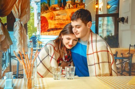 beautiful young couple in love on a date in an outdoor cafe heated under blanketの写真素材