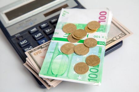 banknotes lie on a calculator. dollars, euros and coins. concept of financial crisis and savings
