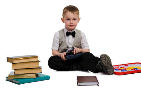elegant little schoolboy studying and looking at the camera isolated on white backgroundの写真素材