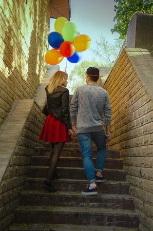 couple walks outdoors with a lot of colorful balloons in her handsの写真素材