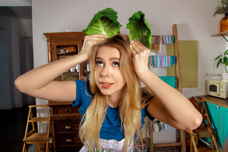 beautiful woman housewife having fun in the kitchen with cabbage leavesの写真素材