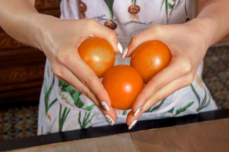 girl holds three tomatoes in handsの写真素材
