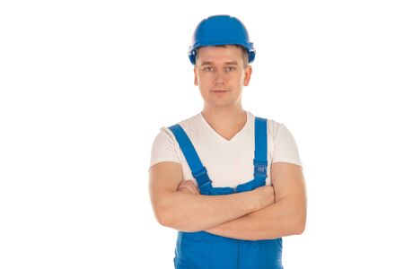 young male builder with crossed hands looking at the camera in blue uniform and helmet isolated on...
