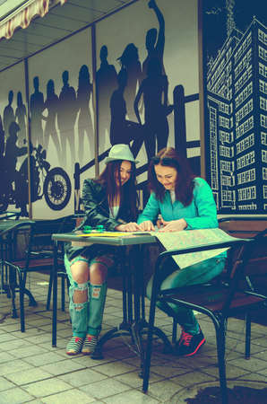 Two girls tourists exploring the city map in street cafes and having funのeditorial素材