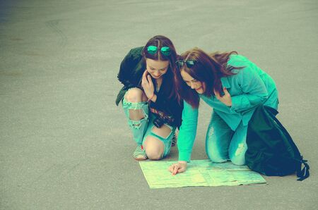 Tourists sitting on the pavement in the square and learn the city mapの写真素材