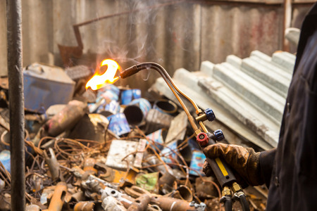 Hands in gloves with welding machine with the garbage on background