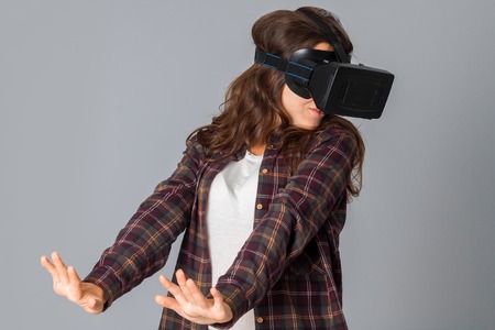 portrait of handsome woman in virtual reality helmet in studio on grey backgroundの写真素材