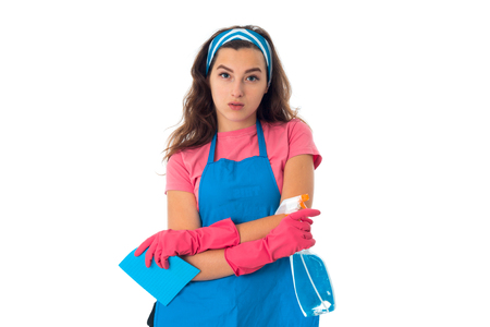portrait of young maid woman in an apron with cleansers isolated on white backgroundの写真素材