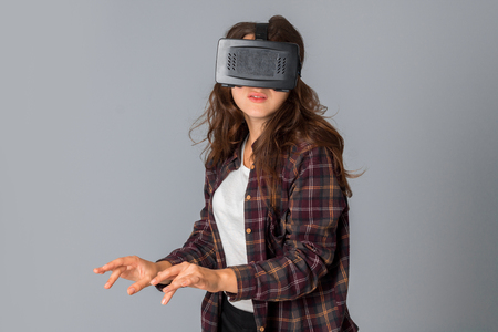 portrait of young beauty girl in virtual reality helmet in studio on grey backgroundの写真素材
