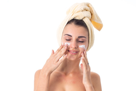 lovely Young girl takes care her skin with towel on head smeared with cream isolated on white background. Health care concept. Body care concept. Young woman with healthy skin.の写真素材