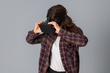 portrait of beautiful woman in virtual reality helmet in studio on grey backgroundの写真素材