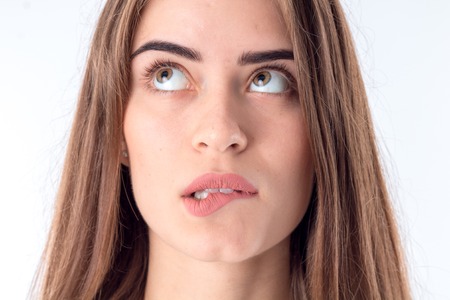 young girl who bites lip and raised her eyes up close-upの写真素材