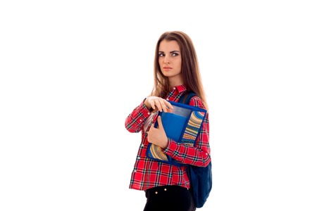 portrait of young serious student girl with backpack and folders for notebooks isolated on whiteの写真素材