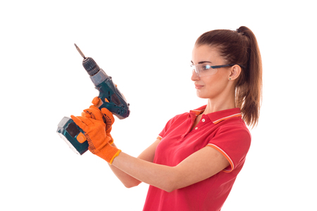 pretty brunette lady makes refurbish an apartment with drill in hands isolated on white backgroundの写真素材