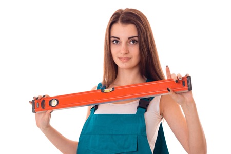 portrait of young adorable brunette builder girl makes renovation isolated on white