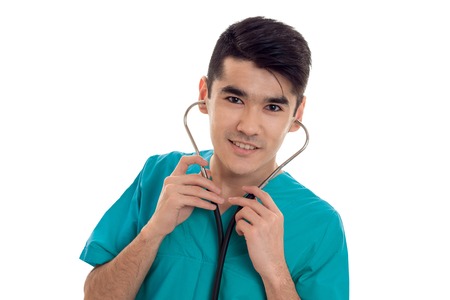 beautiful young male doctor in uniform with stathoscope posing isolated on whiteの写真素材