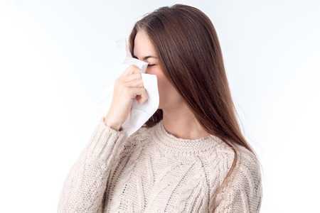 girl in the sweater keeps near the nose Hanky isolated on white backgroundの写真素材
