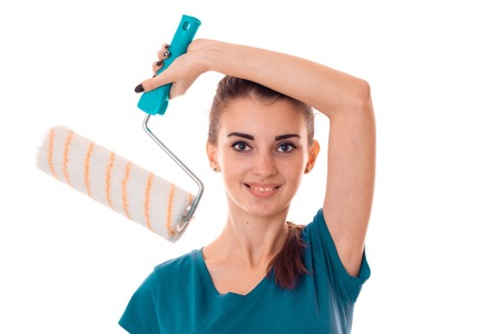 attractive young slim builder girl makes renovations with paint roller isolated on whiteの写真素材