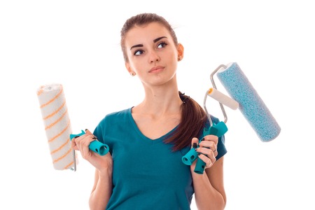 young girl with thoughtful person holds rollers for painting walls and looks toward close up isolated on white backgroundの写真素材