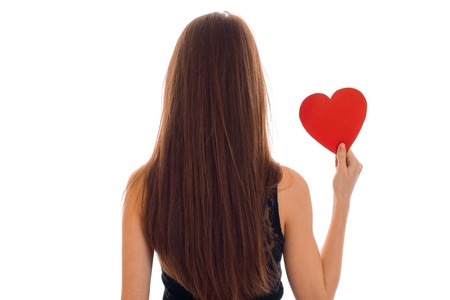 backside portrait of brunette woman in black dress and heart in hands isolated on whiteの写真素材