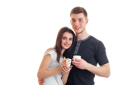 beautiful young couple smiling and holding a cup of tea isolated on white backgroundの写真素材