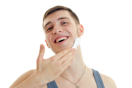 a cheerful young man lifted his head and holds the Palm near beard isolated on white backgroundの写真素材