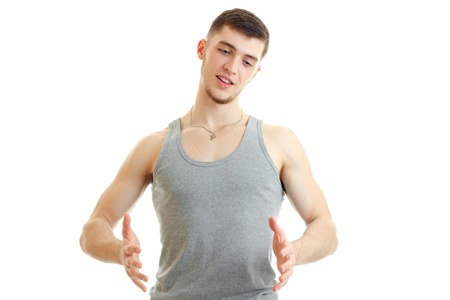 young handsome guy stands up straight and holding hands in front isolated on white backgroundの写真素材
