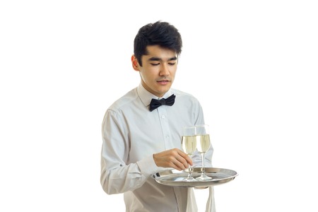 charming young waiter with black hair holding a tray with two glasses of wine isolated on white backgroundの写真素材