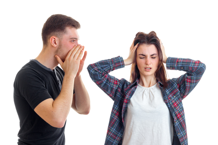young guy yells at the girl and she closed her eyes and ears hands isolated on white background