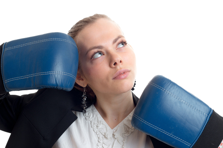 Portrait of a charming blonde that looks up and keeps hands near the person in blue boxing gloves isolated on white backgroundの写真素材