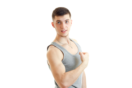 wonderful Sports Guy shows the muscles of the hand and smiles looks at camera isolated on white backgroundの写真素材