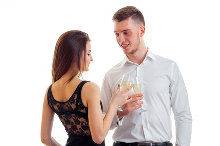 romantic beautiful couple stand opposite each other and carrying glasses of champagne close-up isolated on white backgroundの写真素材