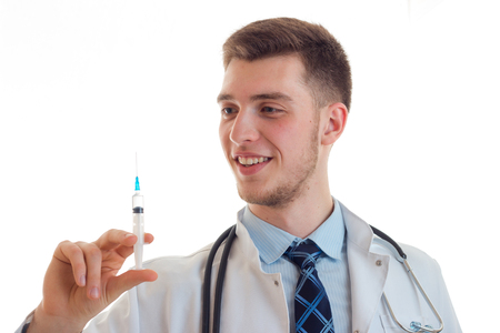 Portrait of a smiling young doctor who holds in his hand a syringe close-up isolated on white backgroundの写真素材
