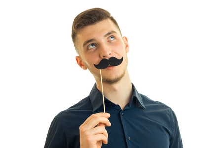 Portrait of a guy with a paper mustache isolated on white backgroundの写真素材