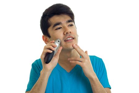 Portrait of a handsome guy with black hair who looks away and shaves isolated on white backgroundの写真素材