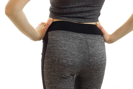 the buttocks of a young girl in Fitness Sports trousers close-up isolated on white background