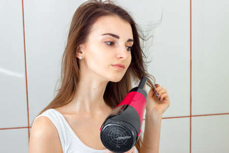 close-up portrait of a young girl that dries hair in the bathroomの写真素材