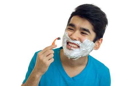 close-up portrait of a beautiful cheerful guy who caused the foam on a beard and shaves isolated on white backgroundの写真素材