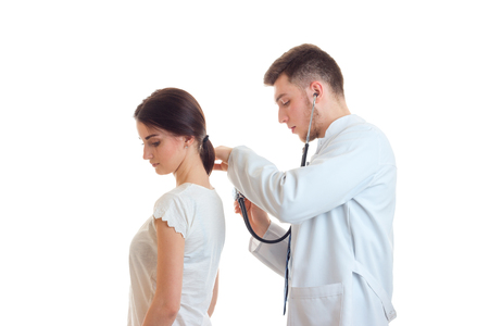 doctor with stethoscope examines a woman patient isolated on white backgroundの写真素材