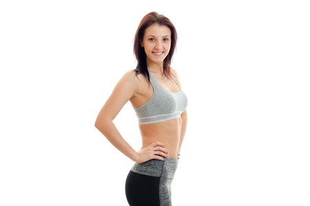 joyful charming young girl stands in the Studio at the sports top and smiling isolated on white backgroundの写真素材