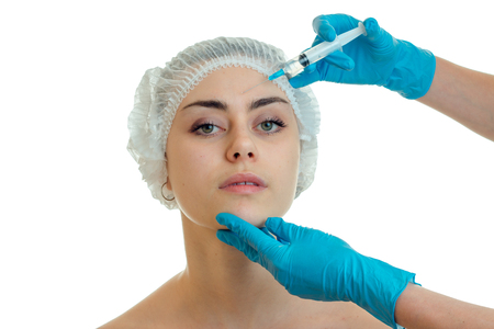 cosmetologist in gloves makes procedures on the face of a young girl have close-up isolated on white backgroundの写真素材