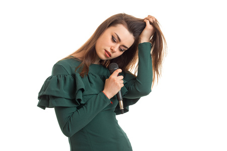 cute girl in a green dress sings in a microphone isolated on white backgroundの写真素材