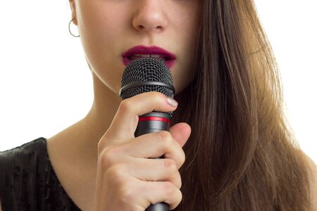 close up of woman with red lips hold a microphone at her mouth isolated on white backgroundの写真素材