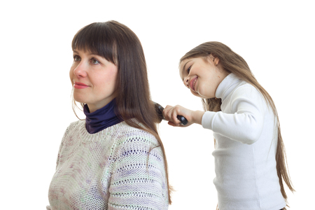daughter combs a long hair of her mother isolated on white backgroundの写真素材